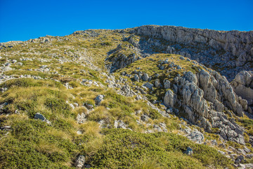 high rock mountain landscape with bare stones and grass background surface hiking place and blue sky