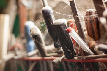 Fototapeta na wymiar Abandoned tool rack near the barn window. Tools covered in cobwebs. 