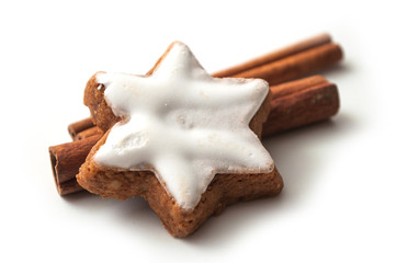 closeup of christmas biscuit shaped star with cinnamon stick on white background