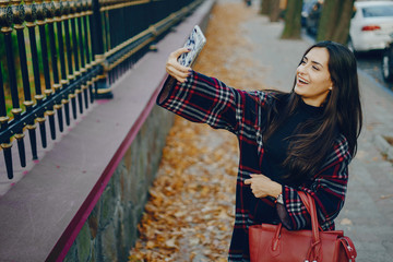 Obraz na płótnie Canvas girl using her cell phone while walking through the park