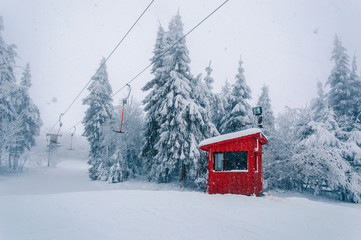 Empty t-bar lift and wooden building at snowfall