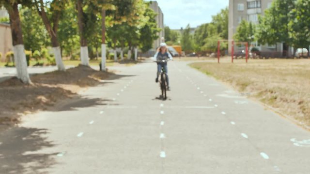 An eleven-year-old girl in a good mood rides a bicycle and after a stop shows a thumbs-up.