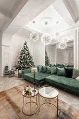 Christmas evening. classic luxurious apartments with decorated christmas tree. Living hall large mirror, green sofa, high windows, columns and stucco.