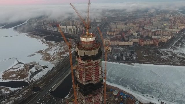 Fly above unfinished building scyscraper construction. Video captured by copter