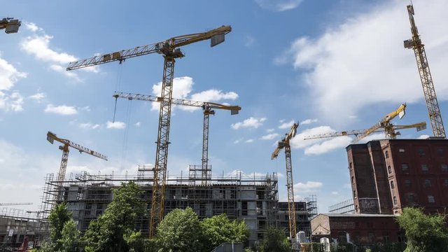 Operating cranes at building construction site, timelapse