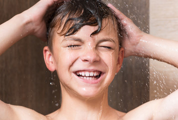 Happy boy washing head in shower in the bathroom - close up portrait