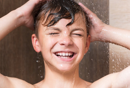 Happy boy washing head in shower in the bathroom - close up portrait