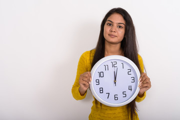 Studio shot of young Indian woman holding wall clock showing the