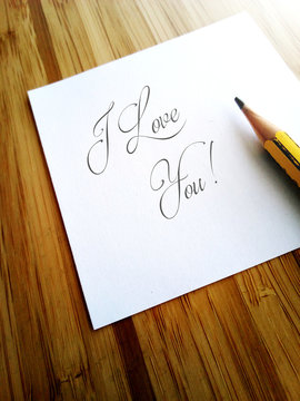 Handwritten message I Love You on white paper note