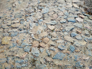 The old stone-paved road, sand and grass are between the stones. Carriageway of granite stone for texture or background.