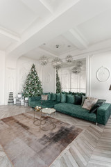 Christmas morning. classic luxurious apartments with decorated christmas tree. Living hall large mirror, green sofa, high windows, columns and stucco.