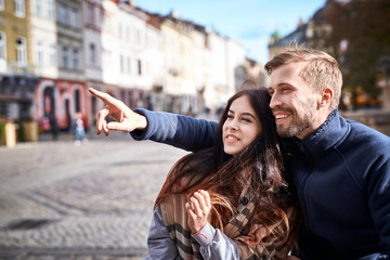 young romantic couple having fun during the city walk at the warm autumn day. happy man and woman on a tour of sightseeing in the city center in Lviv, Ukraine