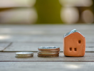 House or Home model on top of coins stack. Concept for loan, property ladder, financial, mortgage, real estate investment, taxes and bonus.