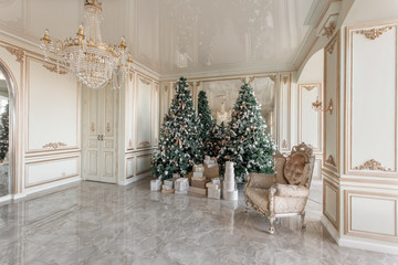 Christmas morning. classic luxurious apartments with decorated christmas tree. Living hall large mirror, chair, high windows, columns and stucco.