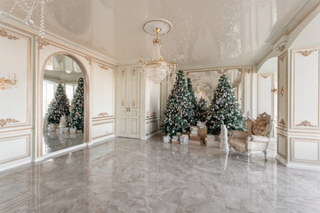 Christmas morning. classic luxurious apartments with decorated christmas tree. Living hall large mirror, chair, high windows, columns and stucco.