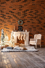 Loft apartments, brick wall with candles and Christmas tree wreath. White wool socks for Santa on the fireplace. Knitted carpet and chair, Christmas tree