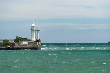 Fototapeta na wymiar seascape with a white lighthouse on the horizon.