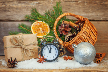 Christmas New Year composition winter objects gift box fir branch basket pine cones balls sled candle alarm clock on old shabby rustic wooden background. Xmas holiday december decoration copy space
