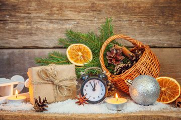 Christmas New Year composition winter objects gift box fir branch basket pine cones balls sled candle alarm clock on old shabby rustic wooden background. Xmas holiday december decoration copy space