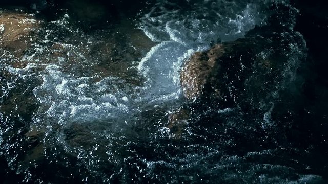 Slow motion of waves on dark water surface with play of flecks of bright light close up. Amazing dramatic natural background. Shooting with 180fps. Epic mystical and magic night view. Crystal clear