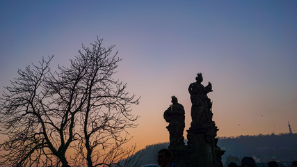 Darkening sunset skies silhouette the statues of the Charles Bridge (Karlův most) on a clear winter night in Prague, Czech Republic (Czechia)