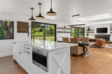 Kitchen in open concept-home with view of living and dining rooms. Interior is white and bright due to skylights.