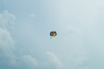 Skydiver flying with a colorful parachute on sky background