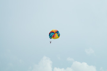 Skydiver flying with a colorful parachute on sky background