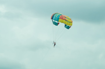 Skydiver flying with a colorful parachute on sky background