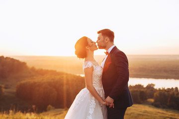 Bride and groom kissing in nature during wedding ceremony