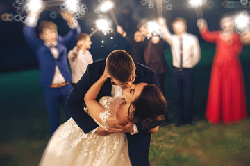 Groom kissing bride during evening wedding ceremony in nature