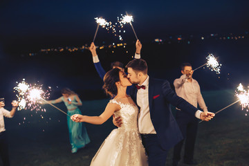 The newlyweds kiss and hold the sparkler