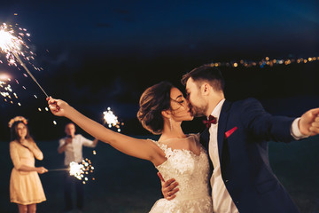 Young couple kissing during the evening wedding celebration