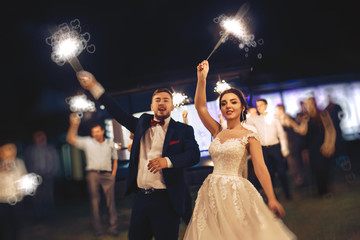 The bride and groom waving Bengal lights