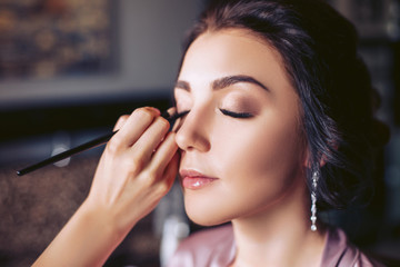 Make-up artist puts make-up on the eyes of a young bride