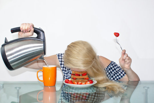 Sleepy young woman had breakfast and put her head in a plate, fell asleep in a plate. Pours water into a mug from a kettle. The concept of early morning, heavy morning.