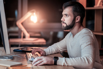 Office life. Concentrated man wrinkling his forehead and pressing lips while creating new program