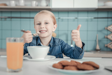 Tasty dish. Happy little satisfied eating in the kitchen girl rejoicing and having dish.