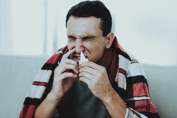 Man with Cold Sitting on Sofa in Checkered Blanket