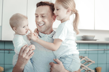 Together and happy. Joyful caring lovely man standing in the bright room smiling and playing with...