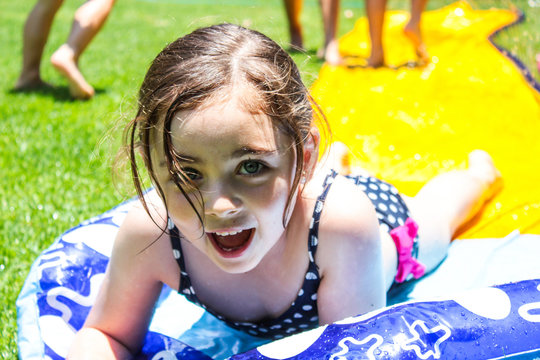 Feliz niña jugando con agua en traje de baño foto de Stock | Adobe Stock