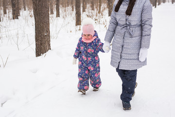 Winter, family and people concept - Close up of young mother is walking with her daughter in winter forest.