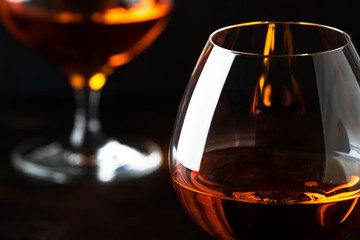 Grape brandy in shot glass, dark brown background, selective focus