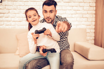 Man and Girl Sitting on Sofa with Joystick in Hand