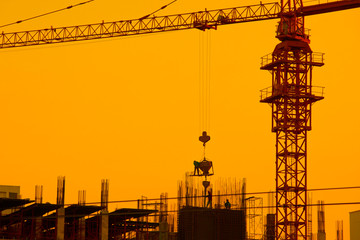Builders are working on construction sites at sunset. Orange background construction site