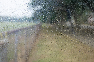  Rain falls on the glass window beside the football field.