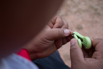 Closeup of man trims his fingernails using a metallic pair of nail clippers