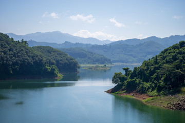 View of Bang Lang Dam water between two mountains and clear blue sky.