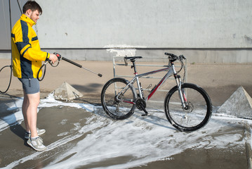 young man washing bicycle at carwash. lifestyle