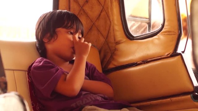 Little boy sucks thumb while alone in a tricycle